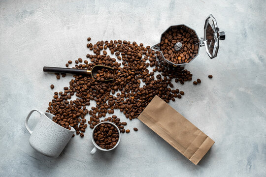 Silver geyser coffee maker with cup and coffee beans from craft bag on gray stone background, top view. Food concept photo