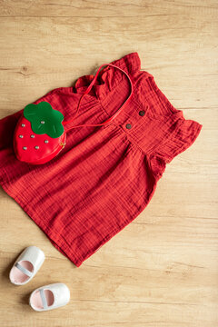 Red baby girl cotton muslin dress with strawberry-shaped handbag, top view