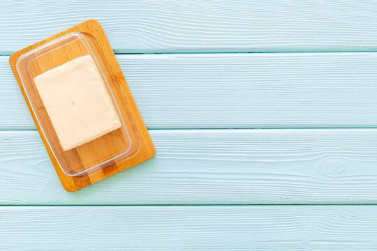 Cut block of fresh butter in wooden butter dish, top view