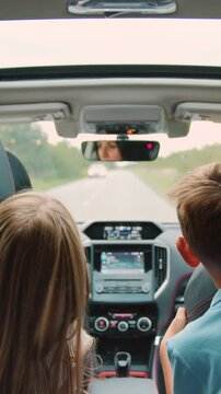 Rear view. Children boy and girl sitting in back seat of car during family trip. Happy family is driving a modern car