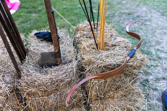 Traditional wooden bow with arrows on hay bales at outdoor archery setup