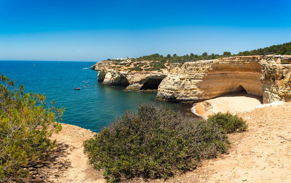 Coastal view of dramatic limestone cliffs under clear blue skies near Portugal's Algarve region