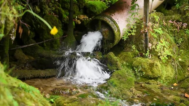 Water from pipe can't turn water mill wheel because of drought and low water level, everything is covered with moss