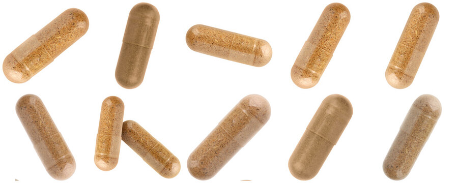 Group of scattered natural herbal supplement capsules with brown powder, isolated on a transparent background.
