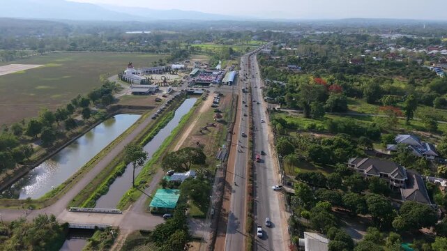 Dynamic 4K aerial jib descent over a regional highway and canal, highlighting urban transit logistics and infrastructure connectivity under bright daylight.