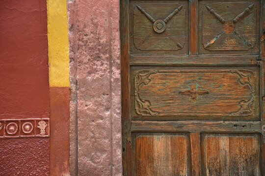 Old Colonial house facade with a Venetian stucco wall and an antique hand carved solid oak wooden door in San Miguel de Allende, Guanajuato Mexico.
