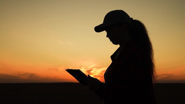Silhouette woman working digital tablet, young girl sunset, human journey digital technology, twilight colors frame a calm silhouette using technology in nature., dusk reflection with digital device