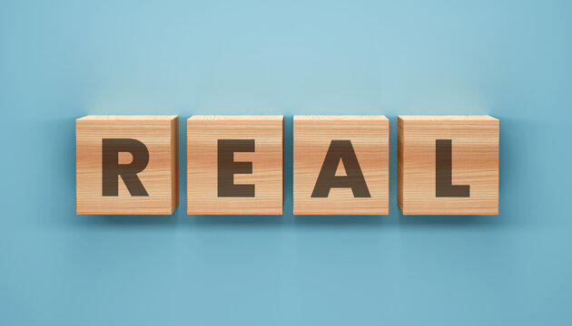 Real World Block Letters: A close-up view presents the word REAL spelled out with wooden blocks, resting on a soft blue surface, symbolizing authenticity and tangible experiences.