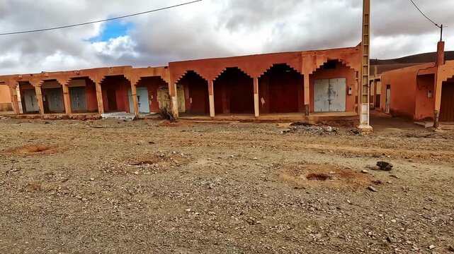 Driving through an abandoned ghost town with traditional ochre buildings in the moroccan desert