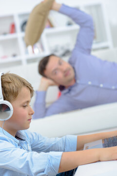 Man poised to throw cushion at young boy on computer