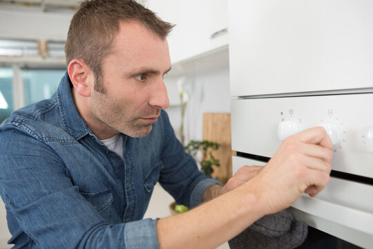 close up of man setting temperature control on oven