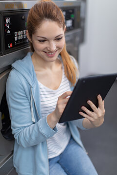 woman using digital tablet at laundromat