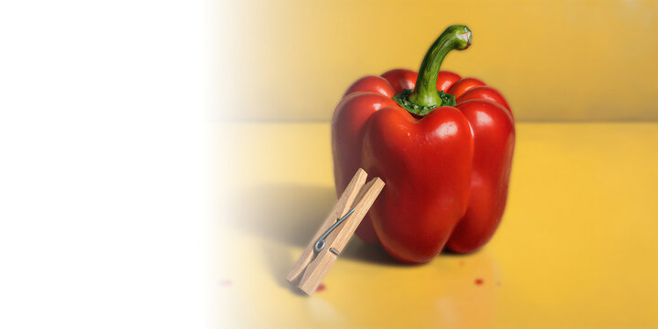 Red pepper with clothespin yellow background minimalist still life