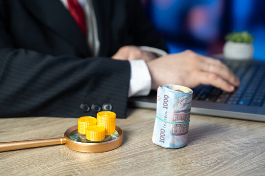 Ukrainian hryvnia currency and a businessman working on a laptop. Concept of the Ukrainian state budget, profit, and income. Assistance to those in need people. Online service