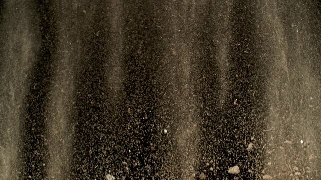 Super Slow Motion Shot of Falling Soil with Rocks on Black Background at 1000fps.