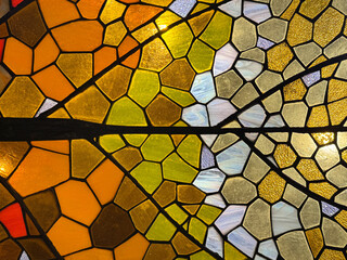 Close up of fish scales or snake scales mosaic tiles made of stained glass in yellow, orange, and white color, with amazing carved leaf veins details. Seamless background texture. © TMR Studio