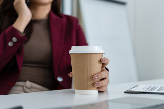 Real Estate Agent Talking on Smartphone with Coffee and Laptop at Office Desk