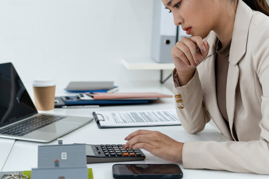 Stressed Real Estate Agent Using Calculator for Mortgage Planning at Office Desk