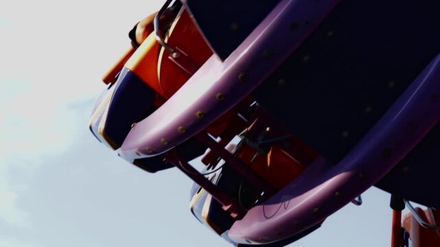 Dynamic video clip showcasing a segment of a rotating amusement ride. The frame focuses on the vibrant blue and gold seating compartments, accented by black safety bars and a bright yellow handle.