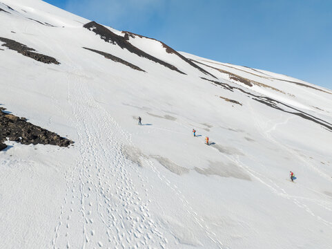 Aerial view of Versante sud dell' Etna with people hiking on the snow-covered volcanic slope under a clear blue sky Nicolosi, Sicilia, Italy.