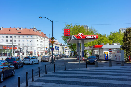 WARSAW, POLAND - MAY 01, 2026: A bustling urban street scene featuring an Orlen gas station, a Rossmann store, and traffic under a clear blue sky.
