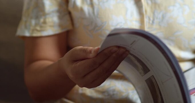 A detailed view of hands flipping through a magazine sparking design inspiration in a warm setting.