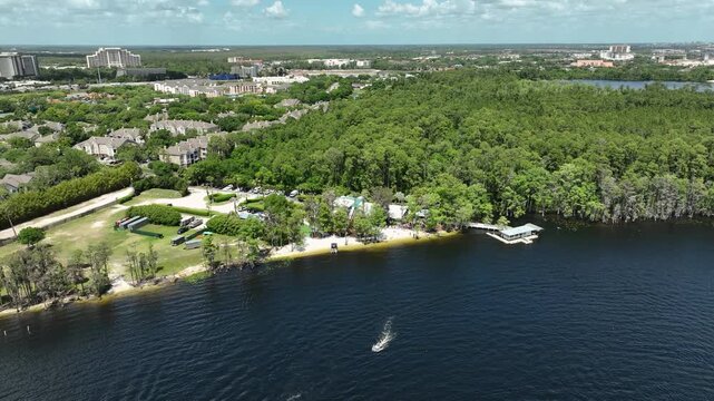 Cinematic bird's-eye shot of Paradise Cove, Orlando &mdash; a hidden Florida gem with waterfront cabins, a private beach, docked pontoons, and forested shoreline framing the lake.