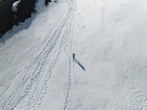 Aerial view of a lone skier crossing the snowy slopes of the south side of Mount Etna with numerous tracks and long shadows Nicolosi, Sicilia, Italy.