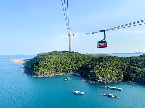 Aerial view of island with lush jungle and coastlines taken from a cable car ride, overlooking vast blue ocean, under a sunny blue sky. Mother earth nature and sky horizon.