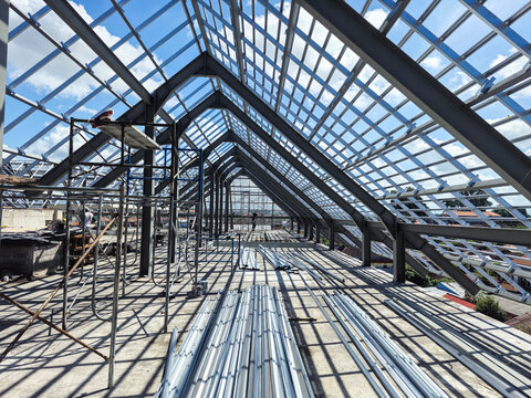 Installation of light gauge steel roof truss system on a modern building construction site. Professional residential framework using durable galvanized steel structures.