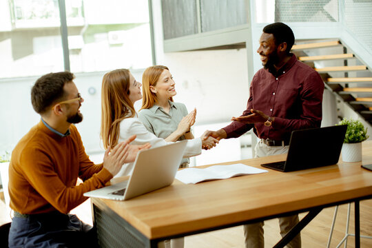 Team members greet a new colleague in a modern office setting during a meeting