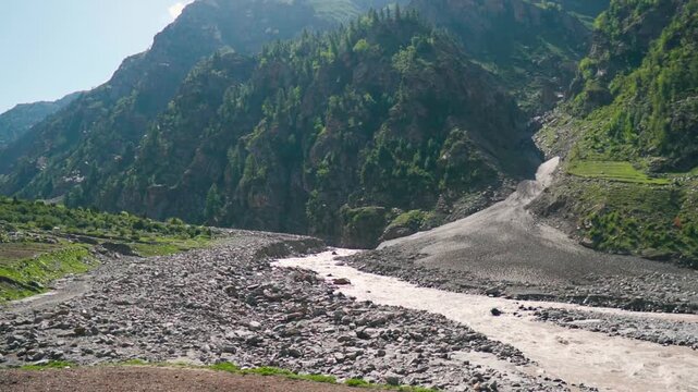 Wide angle shot of farms besides Miyar river in the Himalayan mountain valley during the summer season in Miyar Valley, Himachal Pradesh, India. Farming in the Himalayas background with copy space.