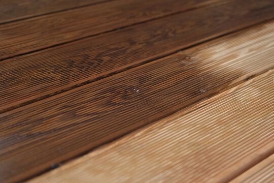 Brown oil for protection of wood by staining. Painting a larch for protecting and pests. Woodworker applying finish to terrace deck board. Repairman varnishing with brush wooden plank floor surface.