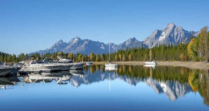 Mountains reflected in the lake, Jackson Lake, sailboats and motorboats in a bay, Colter Bay in autumn, Teton Range mountain range, Grand Teton National Park, Wyoming, USA