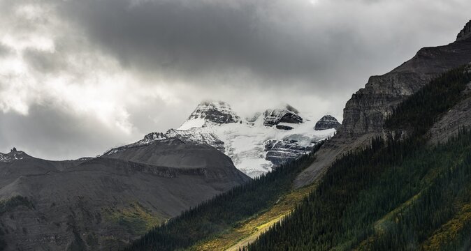 Cloudy snow-capped peaks, Mount Charlton and Mount Unwin, autumnal forest, Maligne Lake, Alberta, Canada