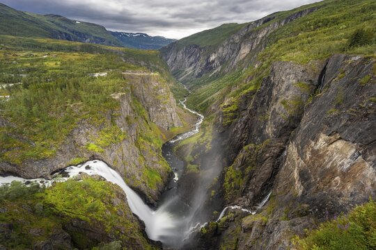 View into the river valley with waterfall V&oslash;ringfossen, river Bjoreio falls down a rock face, valley with river, Eidfjord, Norway
