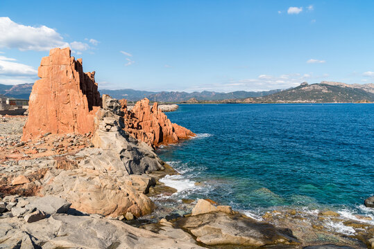 The famous red porphyry rocks known as Rocce Rosse at the port of Arbatax, Sardinia, Italy. Unique coastal landscape featuring striking red cliffs contrasting with the blue Mediterranean Sea.