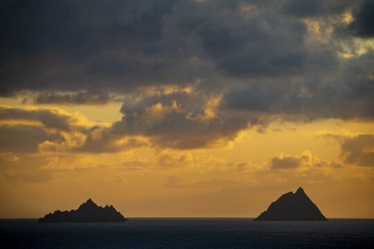Seashore with the mountain peaks of the Skelligs in the background and dramatic cloudy sky, Killarny, County Kerry, Ireland