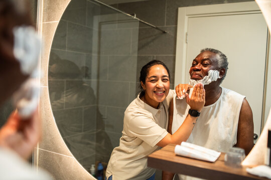 Caregiver helping senior man shave in home bathroom