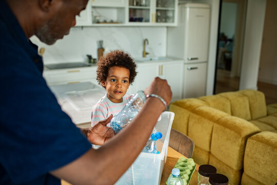 Parent and child recycling plastic bottles in home kitchen