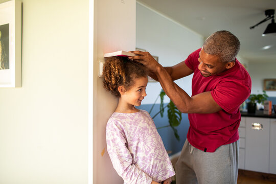 Father measuring daughter's height at home