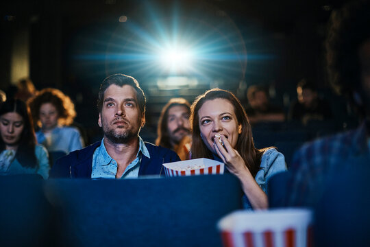 Couple watching a movie with popcorn at the cinema