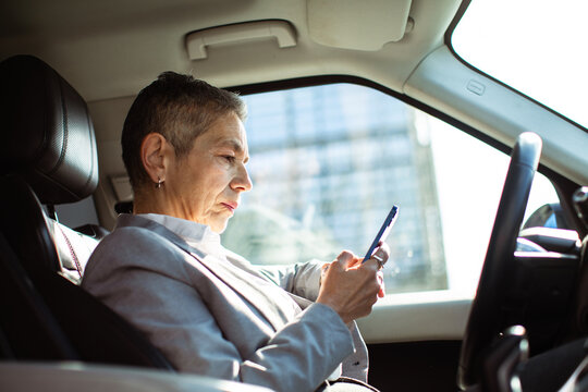 Mature businesswoman using smartphone in parked car