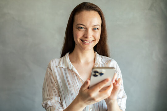 Smiling woman using smartphone at home