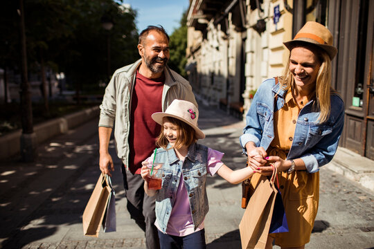 Parents and daughter shopping on sunny city street