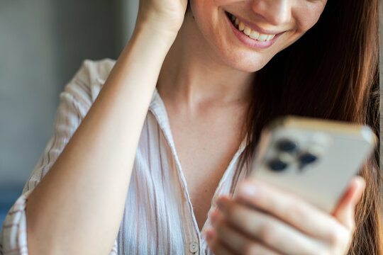 Young woman smiling at smartphone at home