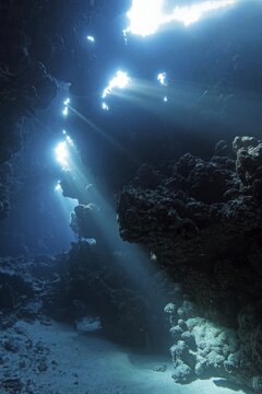 Sunbeams shining through reef top into cave in coral reef, Shaab Claude, Red Sea, Fury Shoals, Egypt