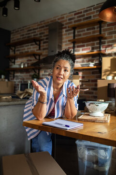 Frustrated mature woman on phone in home kitchen