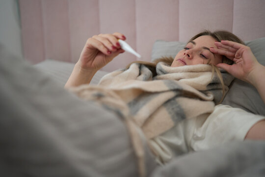 Sick Day Rest with Thermometer in Hand