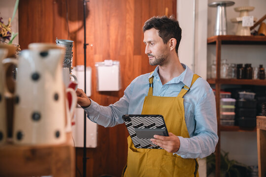 Coffee shop worker using tablet in warm interior